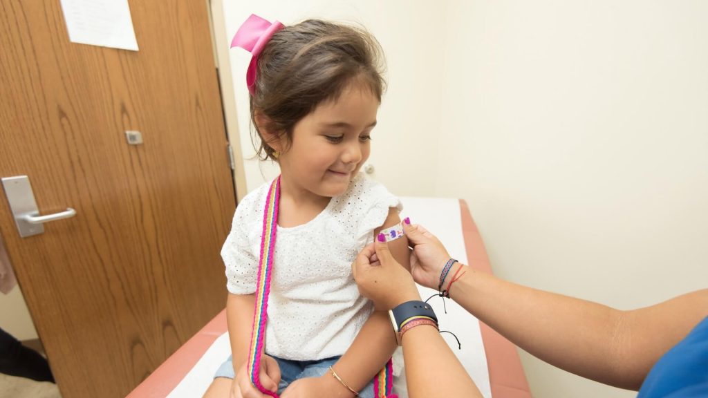 A caring nurse gently places a band-aid on a child's wound, providing comfort.