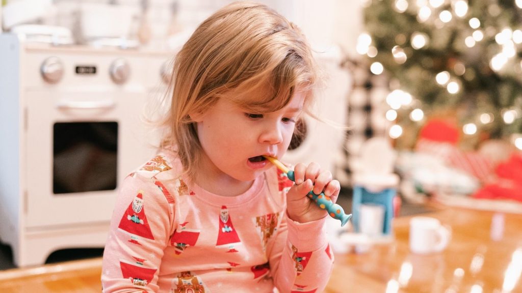 A young child diligently brushing their teeth, maintaining good oral hygiene.